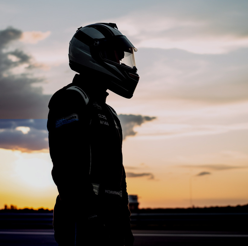 Driver silhouetted against the sky beside a Talbot-Lago racer